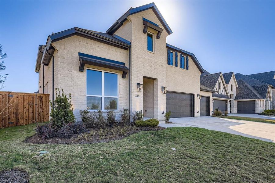 View of front facade featuring driveway, brick siding, and an attached garage