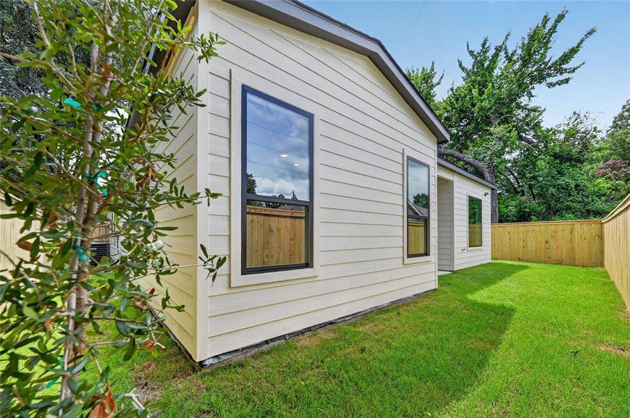Expansive side yard featuring a manicured lawn, newly installed wood privacy fencing, and a young tree Expansive side yard featuring a manicured lawn, newly installed wood privacy fencing, and a young tree
