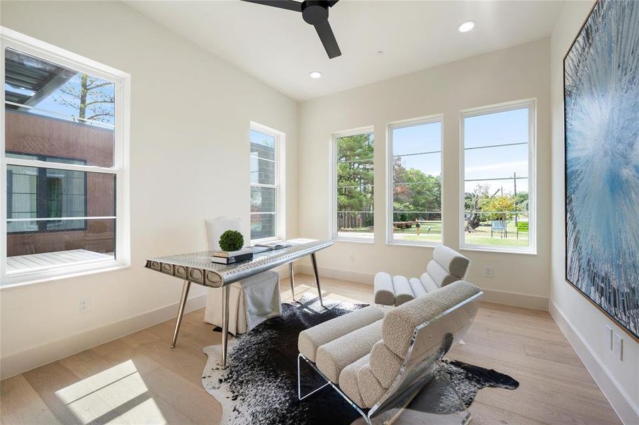 Office with light wood-type flooring and ceiling fan