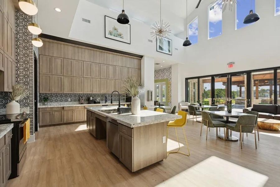 Kitchen featuring a sink, appliances with stainless steel finishes, a high ceiling, backsplash, and an island with sink