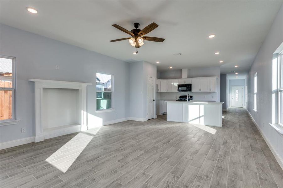 Unfurnished living room with ceiling fan and light hardwood / wood-style floors