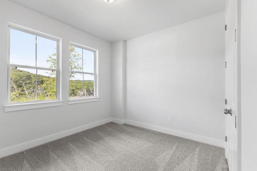 Two well-lit windows frame views of verdant outdoor surroundings in this inviting room. Two well-lit windows frame views of verdant outdoor surroundings in this inviting room.