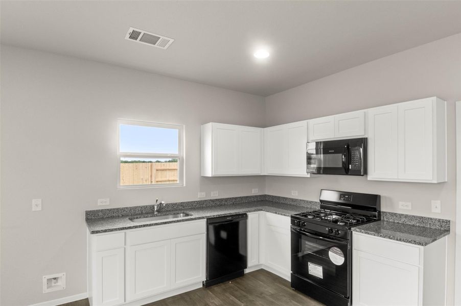 Kitchen featuring black appliances, dark wood finished floors, and white cabinetry