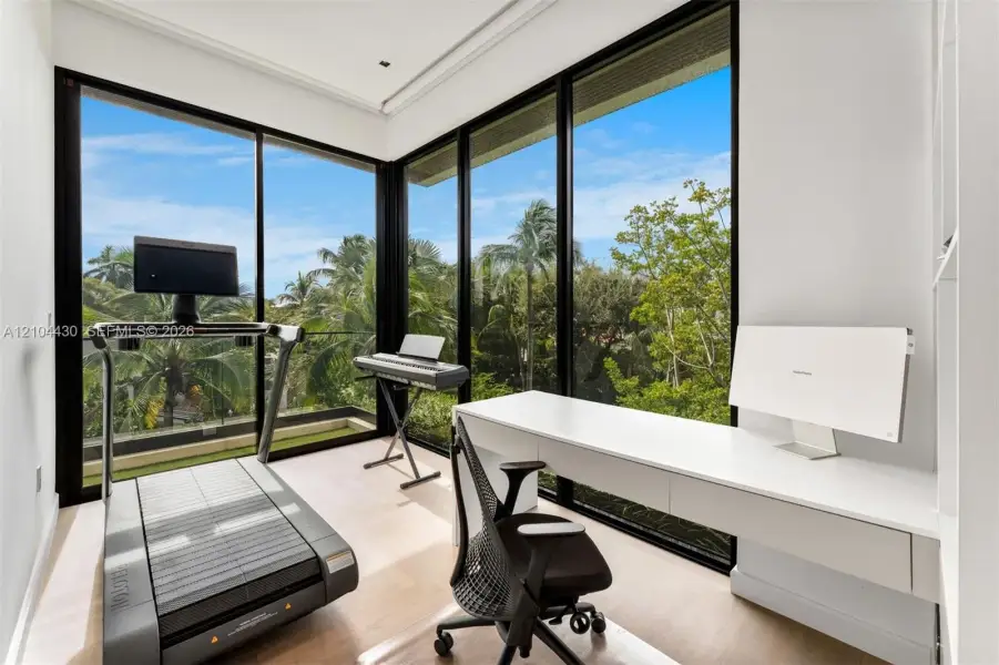 Floor-to-ceiling windows with black frames, wood-finish flooring, and a wall-mounted floating desk