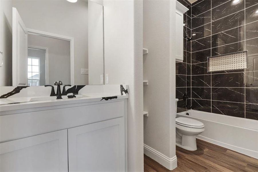 Full bathroom featuring vanity, hardwood / wood-style flooring, toilet, and tiled shower / bath