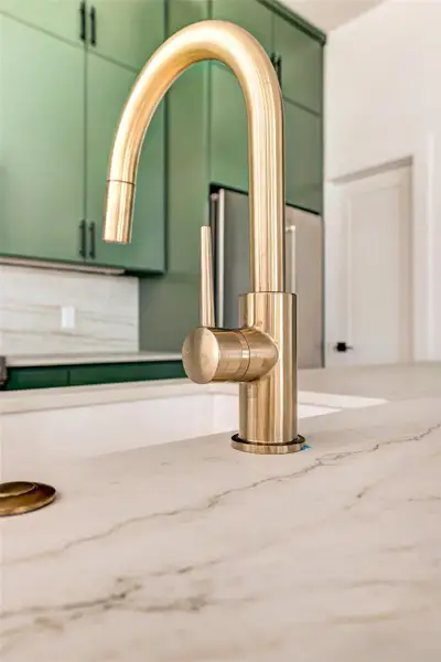 Kitchen view of green cabinets and light stone countertops