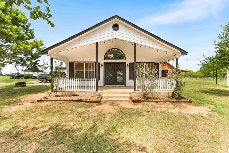 View of front of property featuring covered porch, a front yard, and french doors View of front of property featuring covered porch, a front yard, and french doors