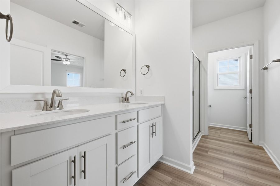 Bathroom with double vanity, light wood-type flooring, a stall shower, a ceiling fan, and plenty of natural light Bathroom with double vanity, light wood-type flooring, a stall shower, a ceiling fan, and plenty of natural light