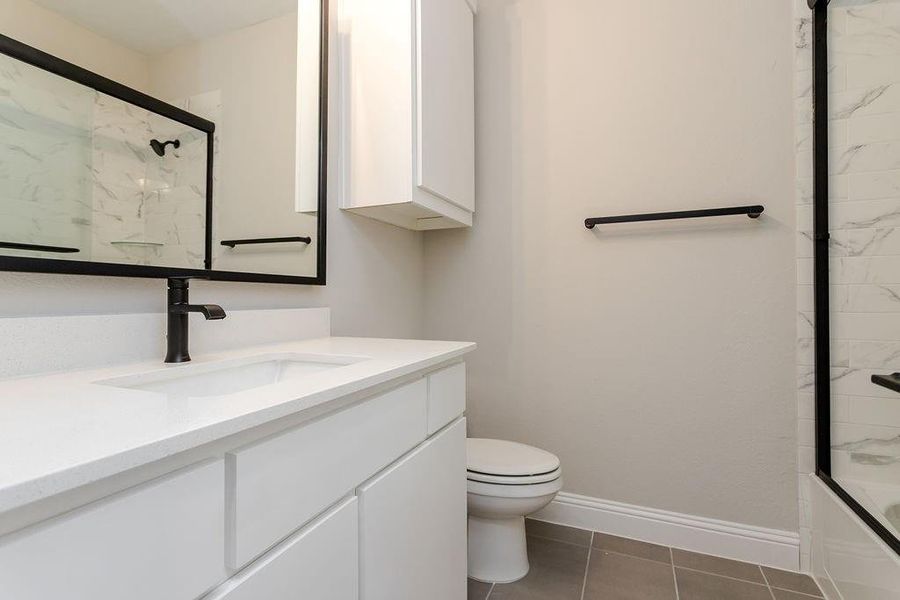 Full bathroom with tile patterned flooring, combined bath / shower with glass door, toilet, and vanity