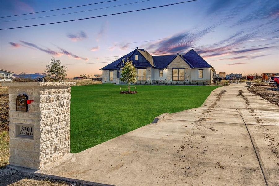 View of front of home featuring stone siding and a front yard