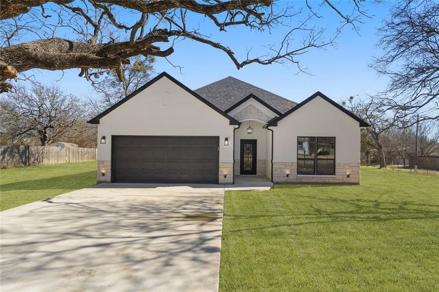 View of front of property featuring a garage and a front lawn