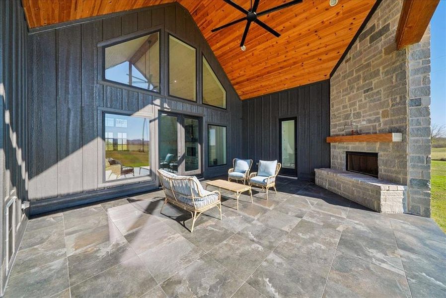 View of patio / terrace featuring a stone fireplace and ceiling fan