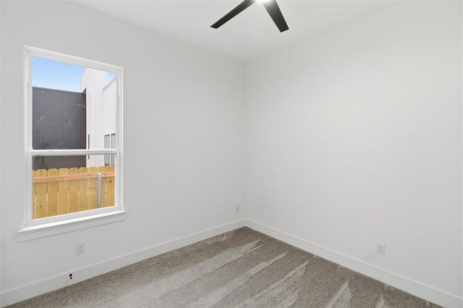 Carpeted empty room with baseboards and a ceiling fan
