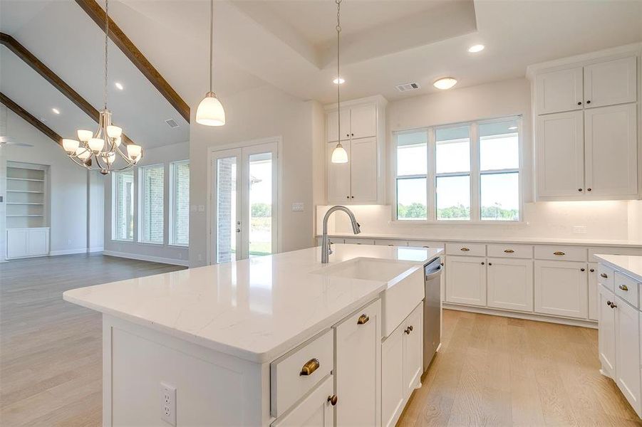 Kitchen with light hardwood / wood-style flooring, dishwasher, beam ceiling, and a kitchen island with sink