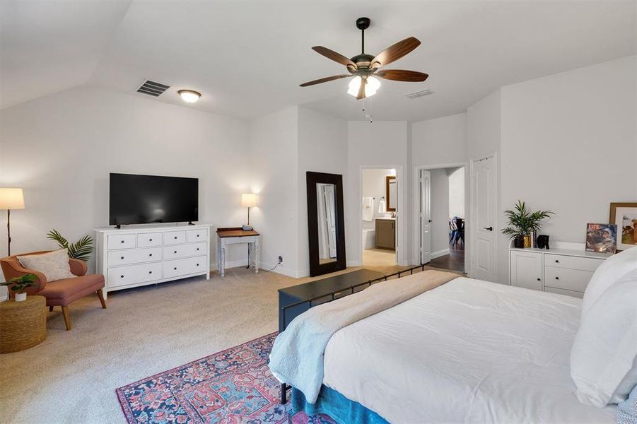 Bedroom with ensuite bathroom, ceiling fan, lofted ceiling, and light carpet