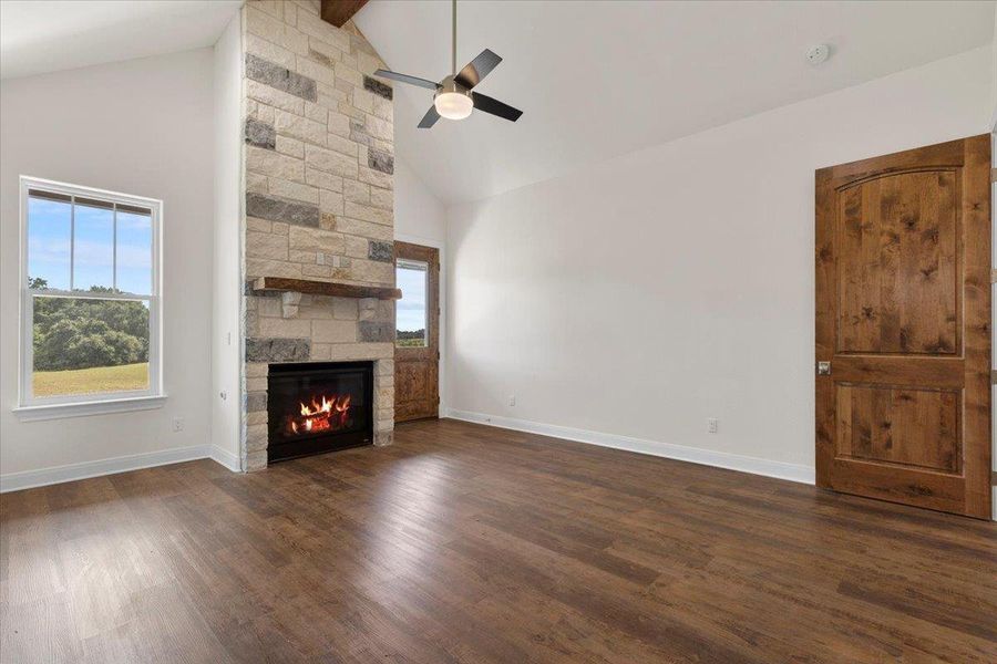 Unfurnished living room with high vaulted ceiling, a fireplace, dark wood finished floors, ceiling fan, and beamed ceiling