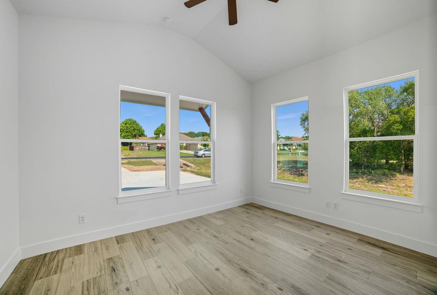 Unfurnished room with light wood-type flooring, lofted ceiling, and ceiling fan Unfurnished room with light wood-type flooring, lofted ceiling, and ceiling fan