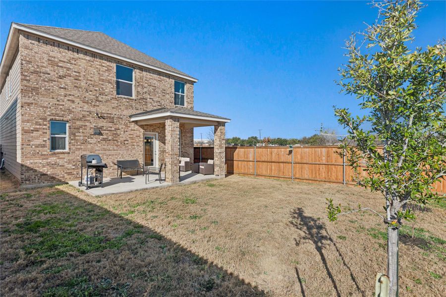 Rear view of house featuring brick, extended covered patio, a fenced backyard, and an outdoor entertainment area
