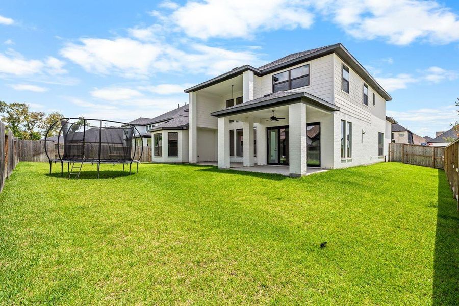 Spacious backyard with lush green lawn, featuring a modern two-story home and a covered patio perfect for outdoor gatherings.