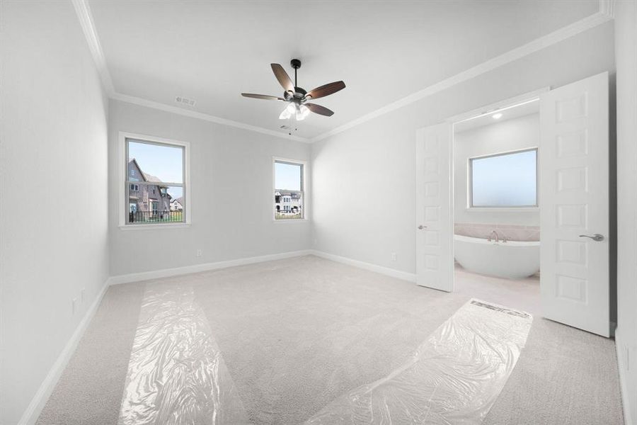 Primary bedroom with natural lighting, crown molding, ensuite bathroom, and ceiling fan.