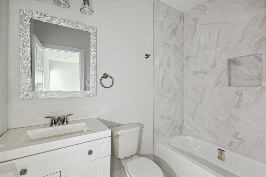 Full bathroom featuring tiled shower / bath combo, vanity, and toilet