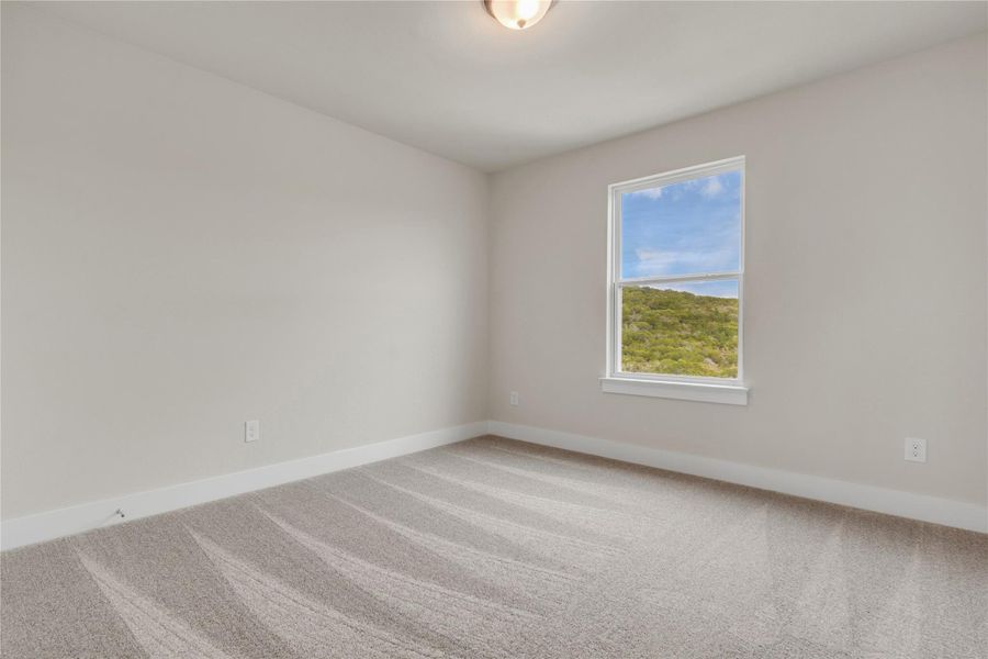 A well-lit room offering peaceful hillside views from a large window.