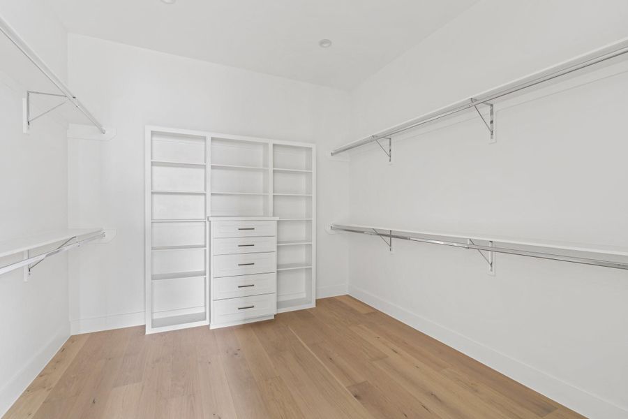 Expansive primary closet with built-in storage solutions, offering ample space and organization. Expansive primary closet with built-in storage solutions, offering ample space and organization.