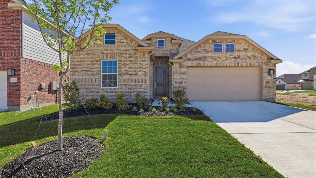 Traditional brick facade residence featuring a two-car garage, concrete driveway, and established landscaping