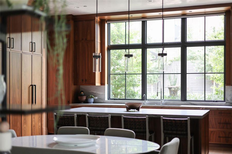 A well-lit kitchen features custom wood cabinetry and a generously sized island with integrated seating.