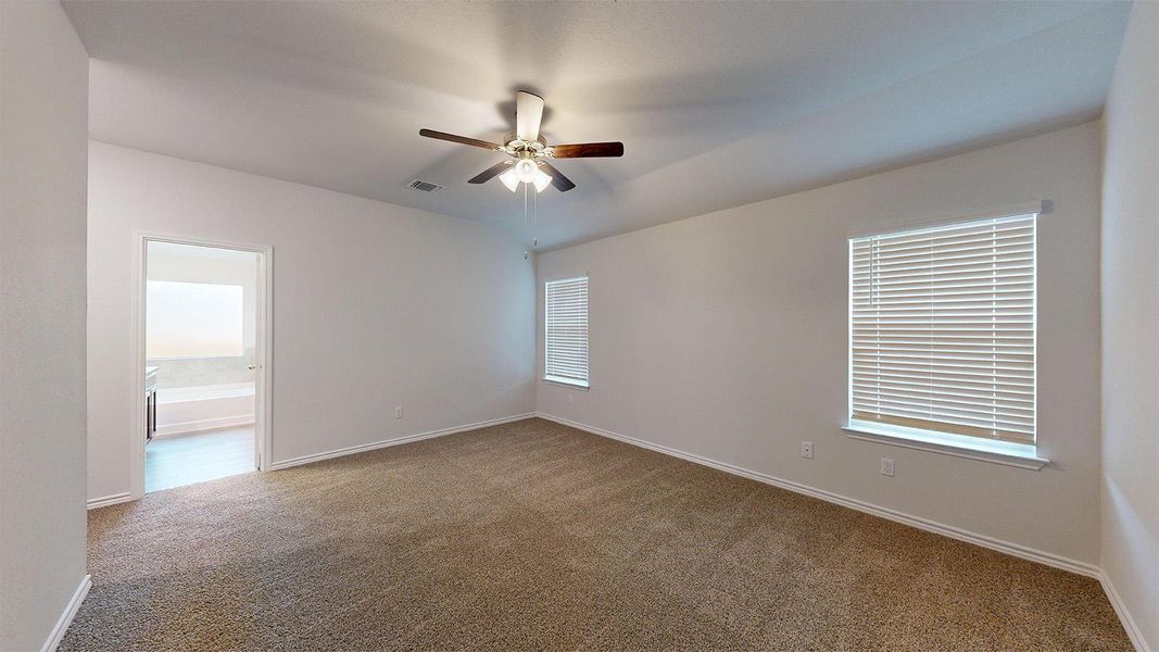 Carpeted empty room with a ceiling fan and baseboards