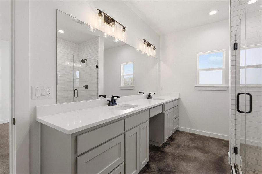 Bathroom with a dual vanity featuring light gray cabinetry and white countertops, a large mirror, and a glass-enclosed shower with subway tile