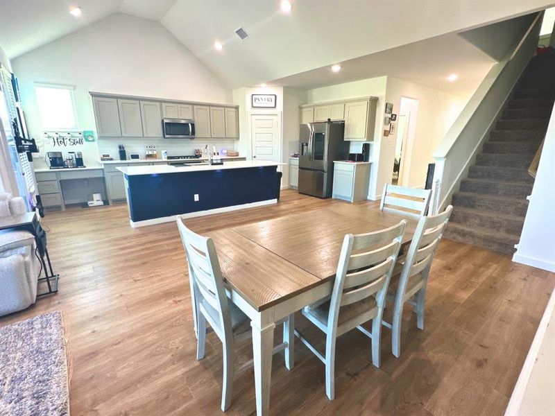 Dining space with high vaulted ceiling, light wood-type flooring, stairway, and recessed lighting