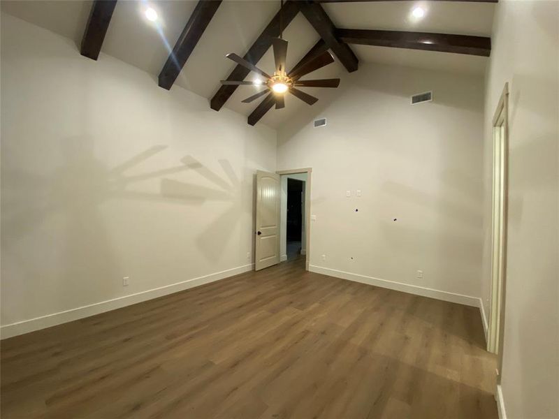 Spare room featuring ceiling fan, dark hardwood / wood-style floors, high vaulted ceiling, and beam ceiling