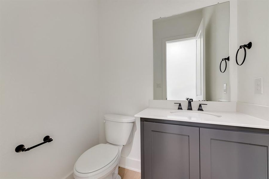 Half bath featuring toilet and vanity Half bath featuring toilet and vanity