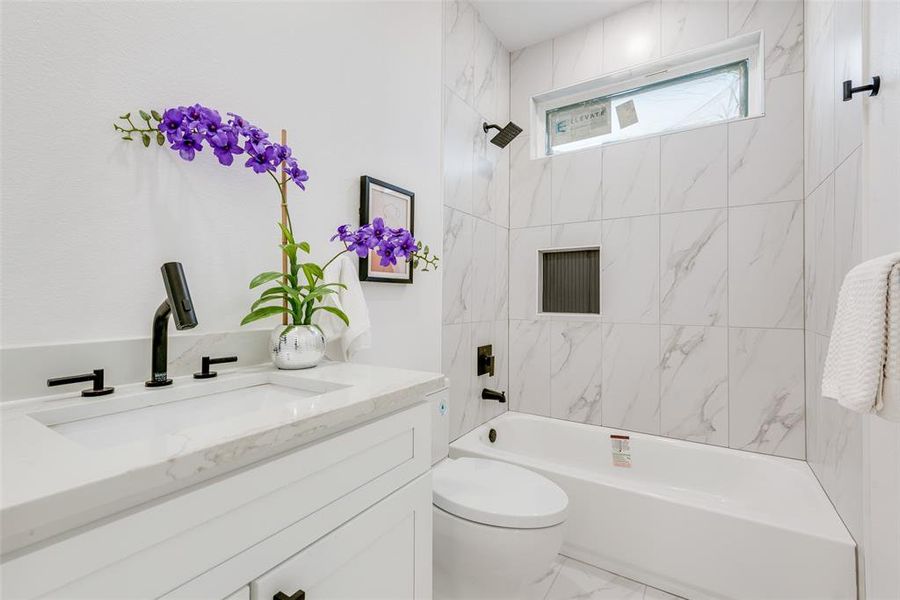 Full bathroom featuring vanity, tiled shower / bath combo, and toilet