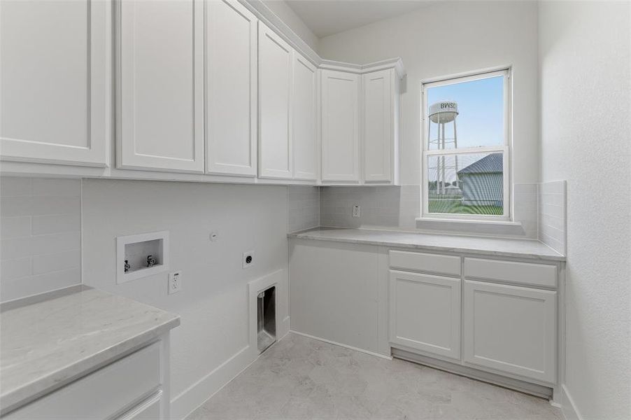 Utility room featuring extensive white shaker-style cabinetry, light-toned countertops, subway tile backsplash, and a window providing natural light Utility room featuring extensive white shaker-style cabinetry, light-toned countertops, subway tile backsplash, and a window providing natural light