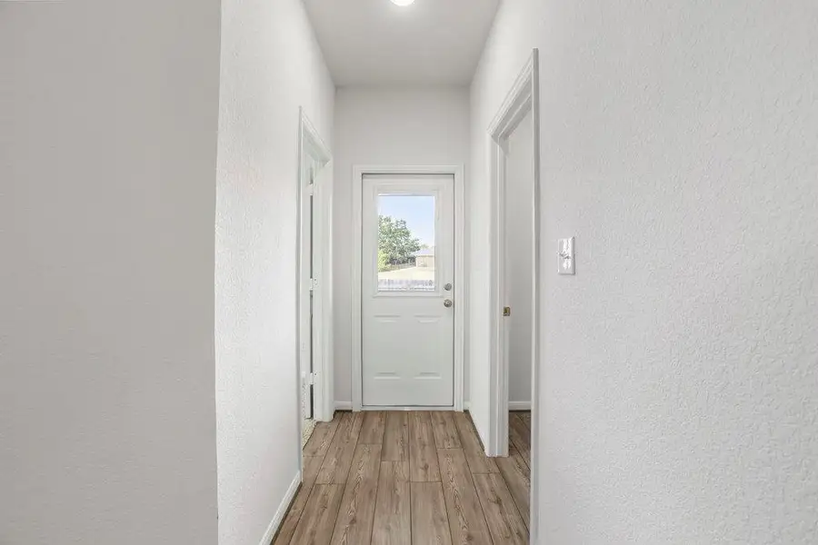 Corridor with a textured wall and light wood-style floors