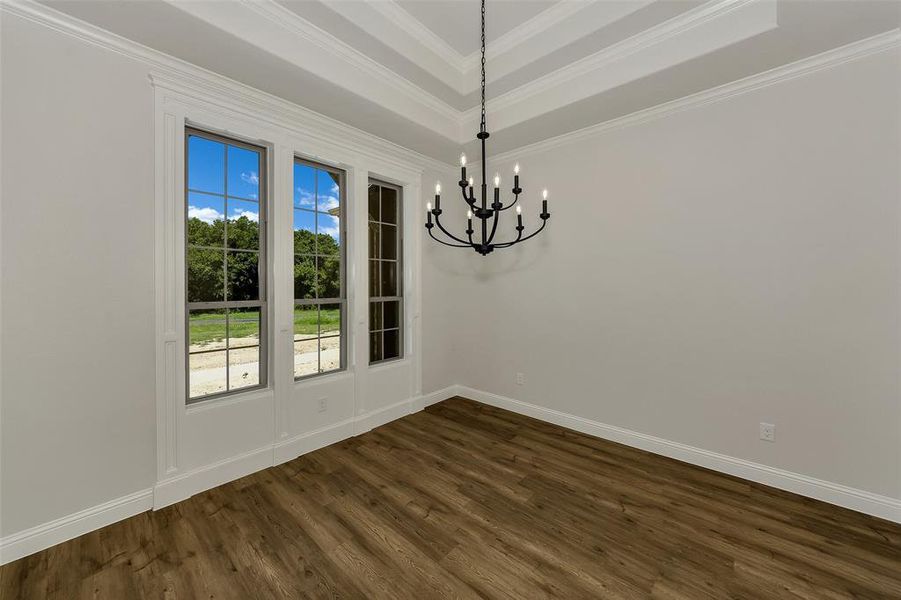 Unfurnished room with a chandelier, ornamental molding, dark wood finished floors, and a tray ceiling