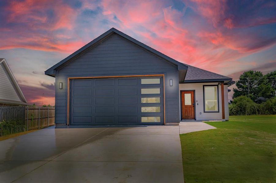 View of front of property featuring a lawn and a garage