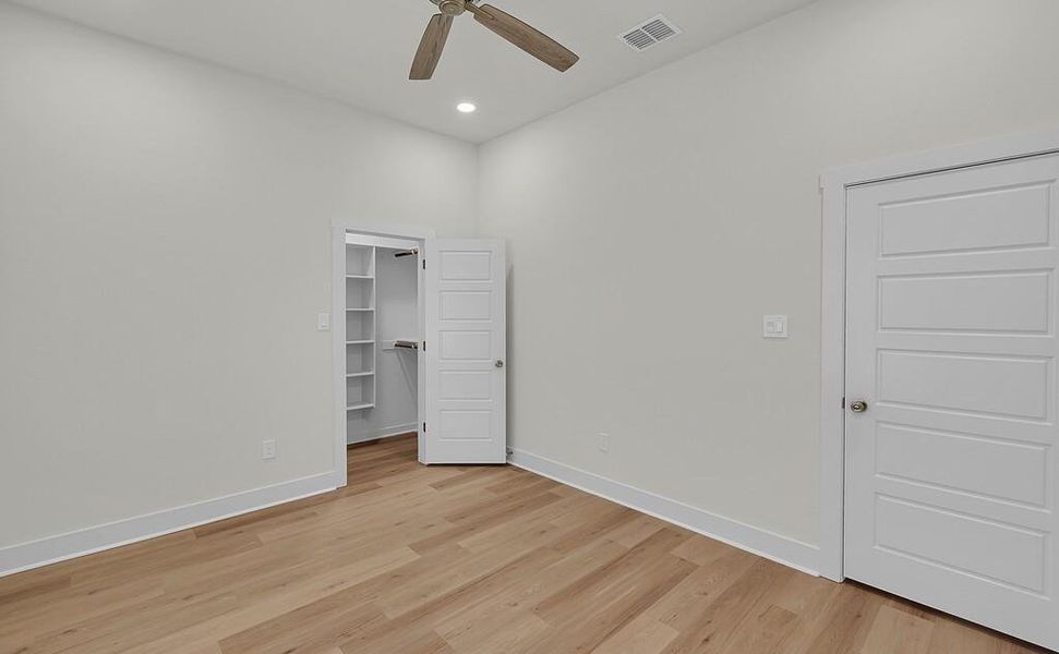 Unfurnished bedroom featuring a spacious closet, light wood-style flooring, ceiling fan, and recessed lighting