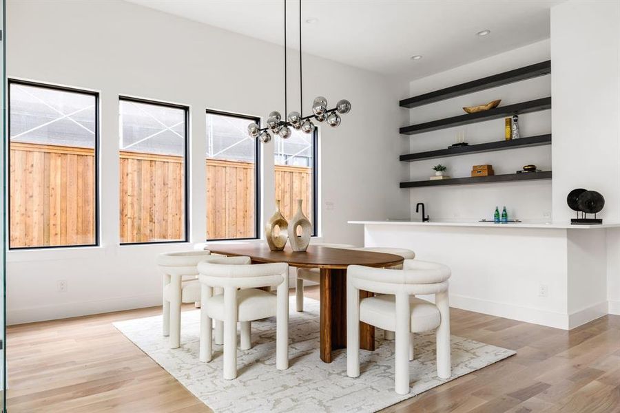 Dining area with light wood finished floors and bar with sink Dining area with light wood finished floors and bar with sink