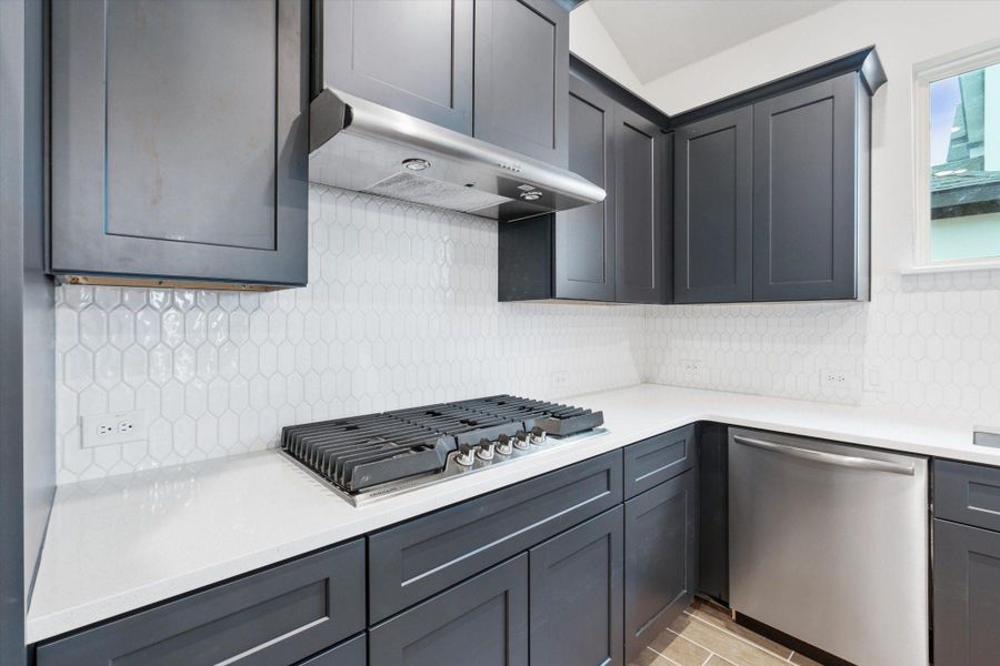 Culinary delights await in this sleek kitchen featuring a gas range, dishwasher, and modern cabinetry.
