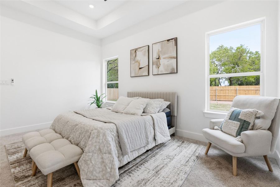 Carpeted bedroom with baseboards and a tray ceiling