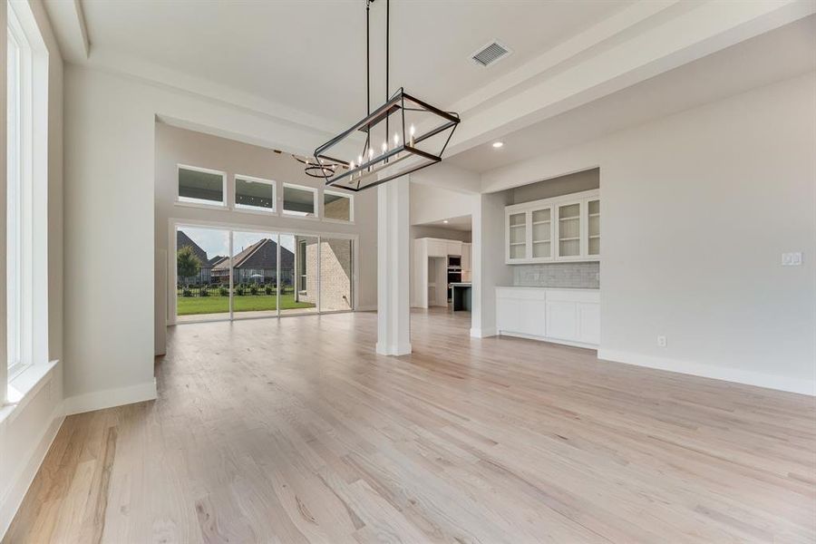 Unfurnished dining area with light wood-style floors, recessed lighting, a chandelier, and a high ceiling Unfurnished dining area with light wood-style floors, recessed lighting, a chandelier, and a high ceiling