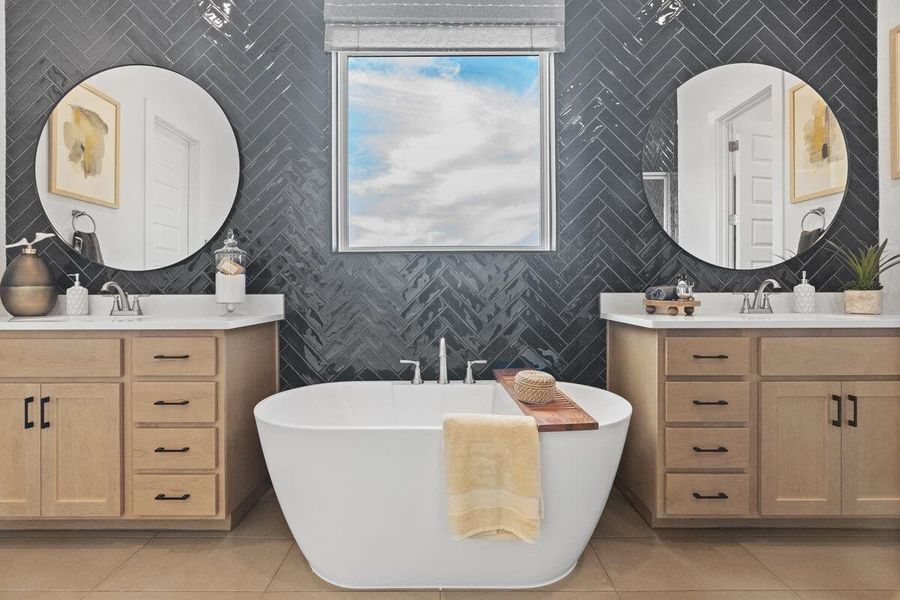 Full bath with a soaking tub, two vanities, tile walls, and light tile patterned floors