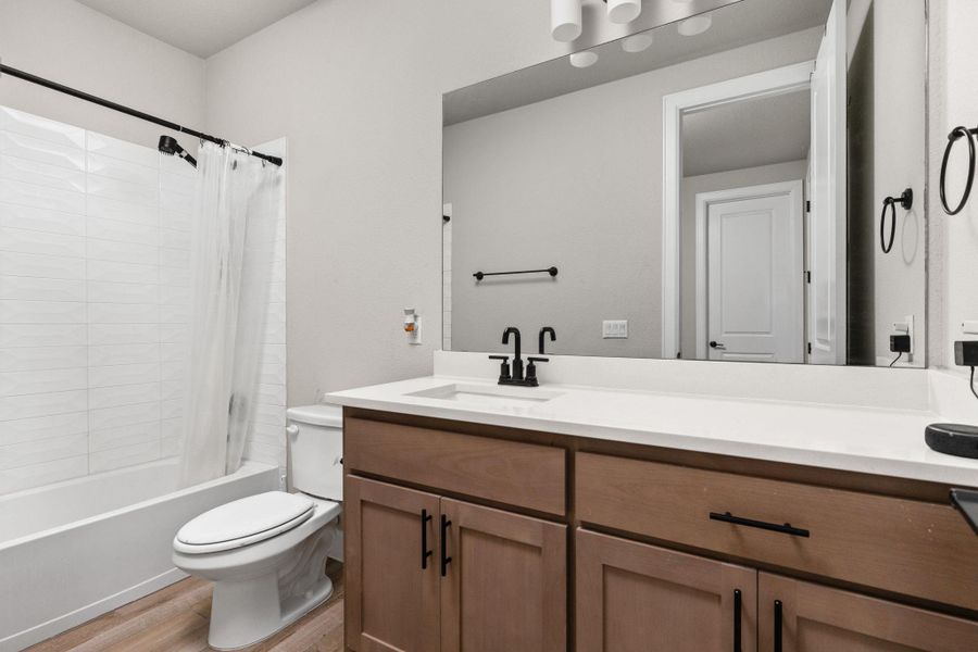 Bathroom with vanity, shower / tub combo, and light wood-style flooring