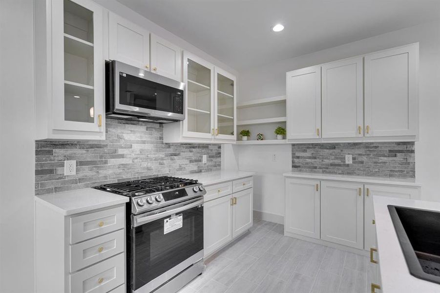 Kitchen featuring backsplash, stainless steel appliances, and white cabinets