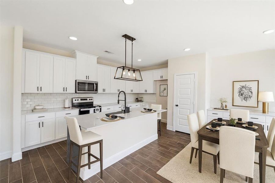 Kitchen with appliances with stainless steel finishes, white cabinetry, decorative backsplash, a kitchen bar, and recessed lighting VS Kitchen with appliances with stainless steel finishes, white cabinetry, decorative backsplash, a kitchen bar, and recessed lighting VS