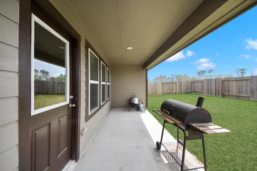 Enjoy outdoor living under the covered backyard patio, offering a shaded space perfect for grilling, relaxing, or entertaining while overlooking the fully fenced backyard.