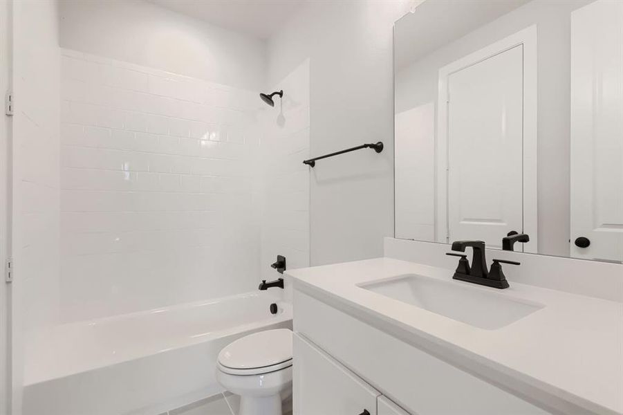 Bathroom featuring a white subway tile shower surround, matte black fixtures, white vanity with integrated sink, a frameless mirror, and a toilet
